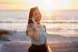 Fresh air will never hurt you. a beautiful young female talking on her cellphone while enjoying time at the beach.
