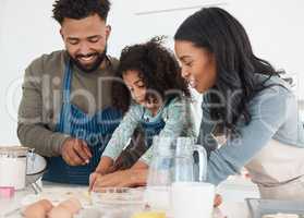 Baking can be fun. an affectionate young couple and their daughter baking in the kitchen at home.