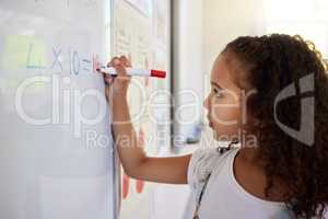 This is simply the best way for little kids to learn. a little girl doing maths on a board in a classroom.