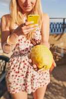 Look at the size of this citron. an unrecognisable woman standing alone and using her cellphone to photograph a citron in Italy.