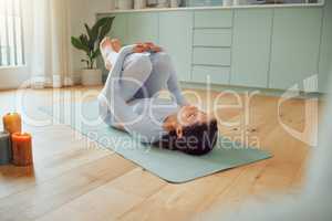 Beautiful young mixed race woman practicing yoga at home. Hispanic female doing pilates exercise as part of her workout. Working out to keep her mind and body healthy. Dedicated to a fitness lifestyle