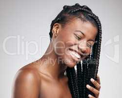 Her skin is as firm as her braids. an attractive young woman posing in studio against a brown background.