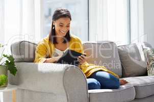 I can tick another thing off my to-do list. a young woman using a digital tablet at home.