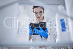 One beautiful young caucasian medical scientist wearing glasses and looking at a digital tablet in a laboratory. Healthcare pathologist discovering a cure in a clinic. Controlling disease with science