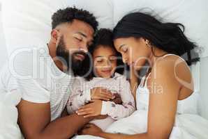 A nap a day keeps the exhaustion away. a young family taking a nap together at home.