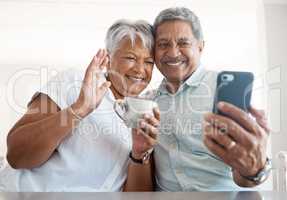 Wave and say hi. a senior couple on a call together at home.