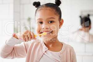 One mixed race adorable little girl brushing her teeth in a bathroom at home. A happy Hispanic child with healthy daily habits to prevent cavities and strengthen enamel