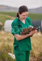 Creating management procedures for better flock health. a young veterinarian writing notes on a clipboard while working on a poultry farm.