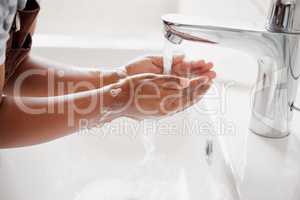 An unknown mixed race child washing their hands in a bathroom at home. Unrecognizable Hispanic child with healthy daily habits to prevent the spread of germs and illness