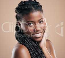 Soft skin and firm braids. Cropped portrait of an attractive young woman posing in studio against a brown background.