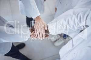 Group of unrecognisable scientists stacking and joining hands in unity and support while standing in a lab at work. Diverse group of lab workers piling their hands from above