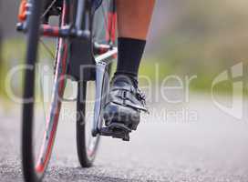 Closeup of the feet of one young woman exercising outside in the forest. Healthy and sporty female athlete with her feet on pedals out for a cycle. Endurance and cardio during a workout in the woods