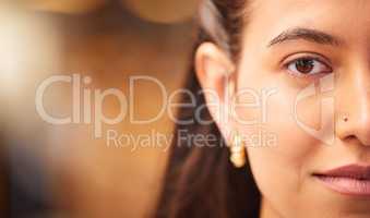 Close up portrait of a beautiful young womans face with smooth flawless skin. Indian female showing off her natural beauty and clear complexion while posing with a nose piercing, half faced