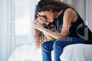Plunging into a deep emptiness and unimaginable void. Shot of a young woman looking sad while holding a teddy bear in a bedroom at home.