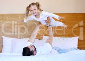 Adorable little girl bonding with her single father at home and pretending she can fly. Caucasian single parent holding and lifting his daughter in the air. Smiling child playing in the bedroom