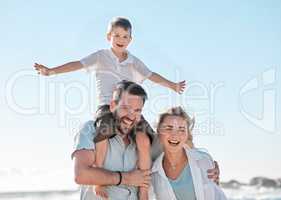 Portrait of happy caucasian parents and playful son having fun in sun against blue sky outside. Carefree dad carrying excited boy on shoulders for piggyback ride and pretending to fly with arms out