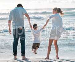 Cheerful caucasian family walking on the beach. Happy family with tone child only having fun at the beach during summer vacation. Child enjoying a getaway with his parents on bright summer day