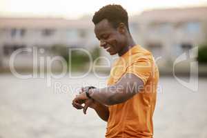 A man looking at his watch and smiling. An African America man in sportswear waiting and smiling at his smartwatch.