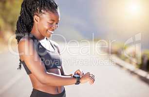 One beautiful african american female athlete checking her smartwatch while exercising outdoors. A young athletic woman smiling while tracking her progress on a fitness watch during her workout