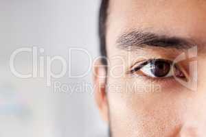 Closeup portrait of a handsome young mixed race man standing at work in an office job. Young hispanic male with naturally long eyelashes and neat eyebrows showing his healthy brown eye