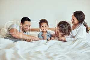 Mixed race Family lying in bed smiling and playing. Latino parents having fun with their little cute kids
