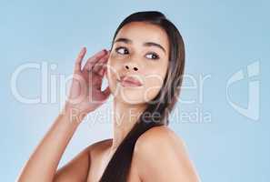 One beautiful young hispanic woman with healthy skin and sleek long hair posing against a blue studio background. Mixed race model with flawless complexion and natural beauty