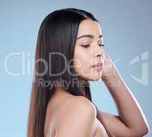 Healthy hair knows no sadness. Studio shot of a beautiful young woman showing off her long silky hair against a blue background.