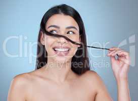 Feeling playful. Studio shot of a beautiful young woman showing off her long silky hair against a blue background.