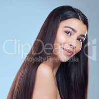 Healthy hair is an investment. Studio portrait of a beautiful young woman showing off her long silky hair against a blue background.