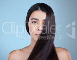 My own idol. Studio portrait of a beautiful young woman showing off her long silky hair against a blue background.