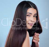 Beautiful in any light. Studio portrait of a beautiful young woman showing off her long silky hair against a blue background.