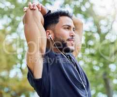 Getting mind and body ready. Shot of a sporty young man stretching his arms while exercising outdoors.