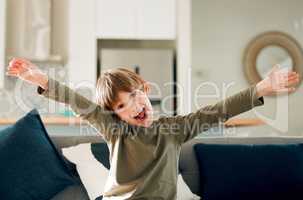 Best day ever. Portrait of a cute little boy expressing excitement while sitting on the sofa at home.