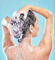 Haircare matters. Shot of a young woman washing her hair in the shower against a blue background.