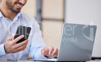 Closeup of business man using smartphone and laptop in office. Man using mobile phone app for synchronizing data with laptop. Getting confirmation message on cellphone