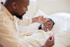 African american father checking his sick daughters temperature while taking care of her at home. Little girl sleeping in bed while her dad checks her fever. Man feeling his daughters forehead