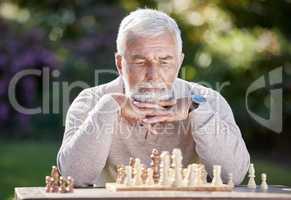 A little bit of luck, a little bit of logic. Shot of a senior man playing a game of chess outside.