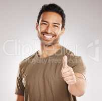 Handsome young mixed race man giving thumbs up while standing in studio isolated against a grey background. Hispanic male showing support or appreciation. Backing or endorsing a product or company