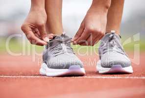 Shes knot in the mood to stumble. an unrecognizable female athlete tying her laces out on the track.