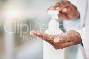 Closeup african american woman doctor sanitizing her hands while in the hospital. Being safe during the corona virus pandemic. Stop the spread of covid 19. Health and safety in the medical field