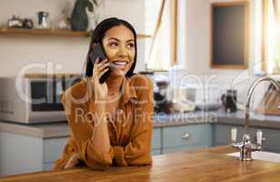 Young happy mixed race woman talking on the phone while relaxing at home alone. One hispanic female in her 20s on a call using her cellphone at home