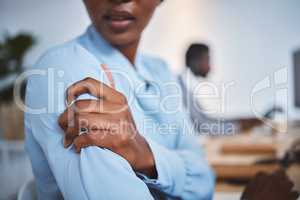 Closeup of one stressed african american businesswoman suffering with arm and shoulder pain in an office. Entrepreneur rubbing muscles and body while feeling tense strain, discomfort and hurt from bad sitting posture and long working hours at desk
