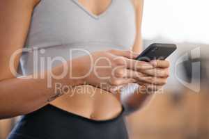 Closeup of one active caucasian woman texting on cellphone with while on break from exercise in a gym. Female athlete browsing fitness apps, social media and watching workout tutorials online