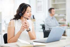 Lets run through the list again. a young businesswoman wearing a headset while having a video call on a laptop in an office.