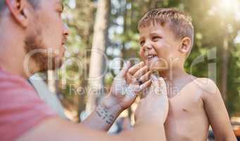 Let daddy help you. a handsome young man putting sunblock on his adorable little son while camping in the woods.