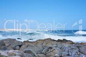Rocks in the ocean under a blue sky with copy space. Beautiful landscape of beach waves splashing against boulders or big stones in the sea at a popular summer location in Cape Town, South Africa