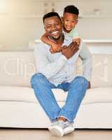 Adorable little african american boy hugging his father while relaxing on a sofa at home. Caring man with his loving son feeling special on fathers day. Single parent spending quality time with child