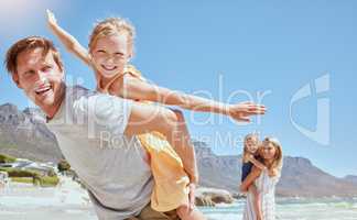 Smiling family with daughters on the beach. Happy man and woman bonding with young adorable girls on holiday. Cute siblings pretending to fly while being carried by their mother and father outside