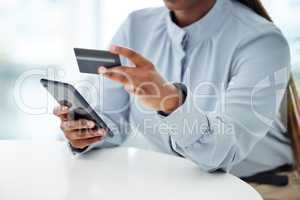 Businessperson using a credit card and phone to shop online at work. One person paying for a purchase using their cellphone. Boss shopping using their phone and bank card