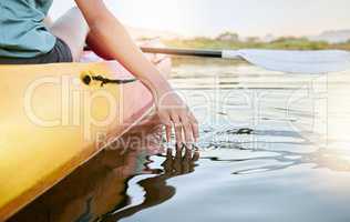 Closeup of female hands kayaking and feeling lake water during the day. Active young woman enjoying water activity while on vacation in summer. Canoeing on calm sunset lake during weekend getaway